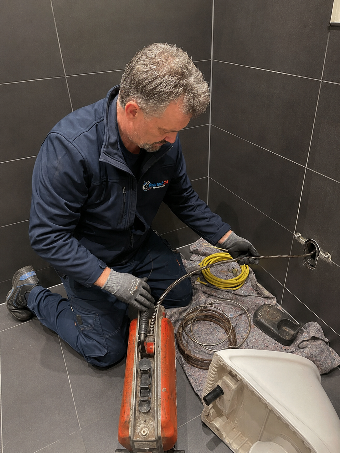 Rohrtech24-Techniker bei einer mechanischen Rohrreinigung in einem Badezimmer